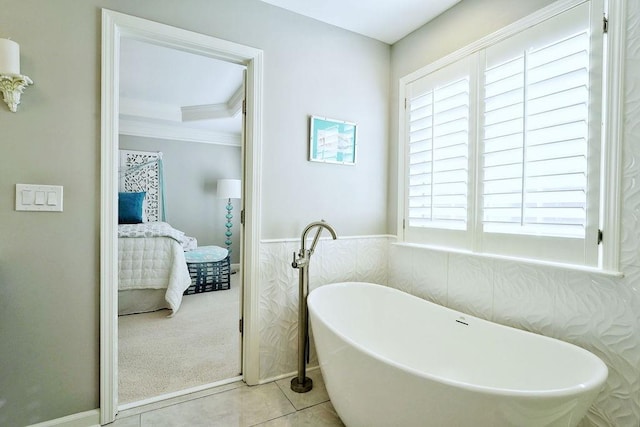 ensuite bathroom with connected bathroom, wainscoting, a freestanding bath, and tile patterned floors