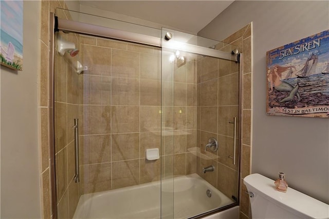 bathroom featuring toilet and combined bath / shower with glass door