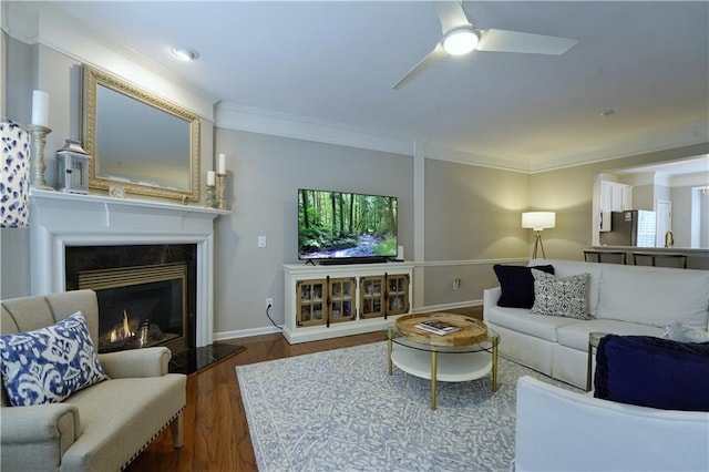 living room featuring a fireplace, dark hardwood / wood-style flooring, ceiling fan, and ornamental molding