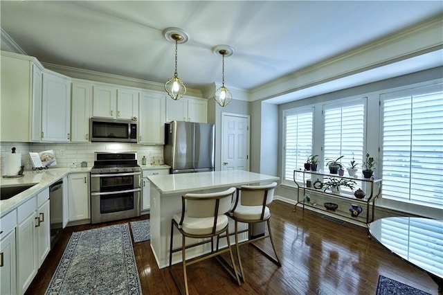 kitchen with white cabinetry, a center island, decorative light fixtures, decorative backsplash, and appliances with stainless steel finishes