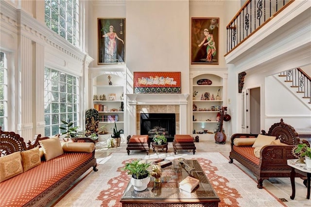 living area featuring stairs, a high ceiling, built in shelves, and a fireplace