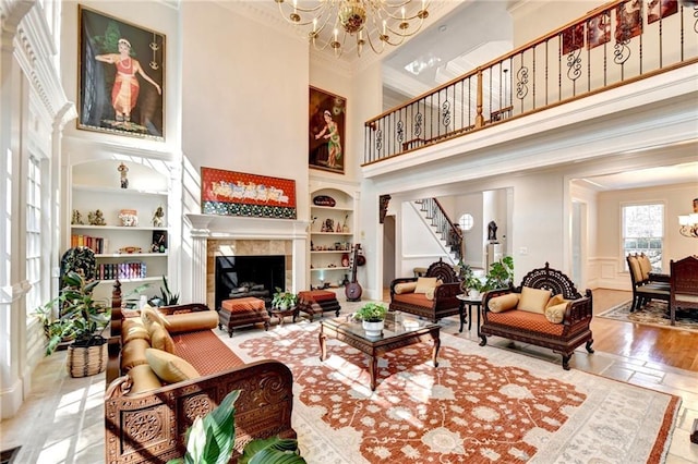 living area with stairway, crown molding, built in shelves, and a chandelier
