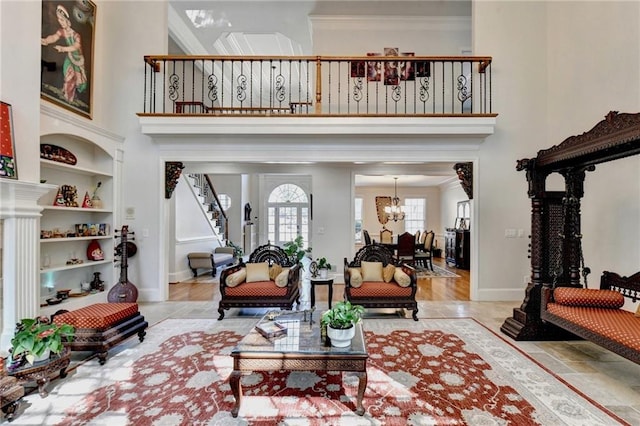 living area featuring crown molding, a towering ceiling, baseboards, stairway, and a chandelier