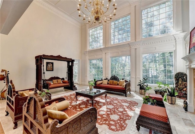 living room featuring an inviting chandelier, crown molding, baseboards, and a towering ceiling