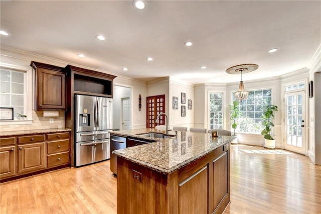 kitchen featuring crown molding, a sink, appliances with stainless steel finishes, and an island with sink