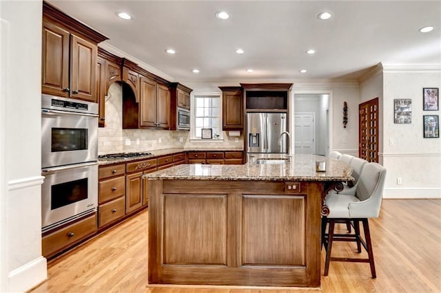 kitchen with crown molding, stainless steel appliances, a sink, and light wood-type flooring