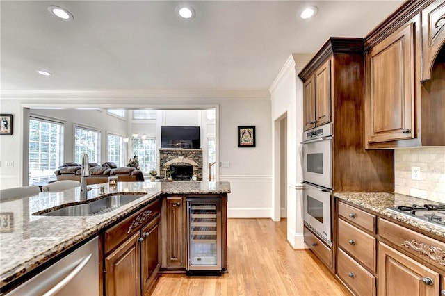 kitchen with beverage cooler, a sink, appliances with stainless steel finishes, and light stone counters