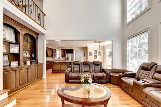 living area featuring plenty of natural light, a high ceiling, and light wood-type flooring