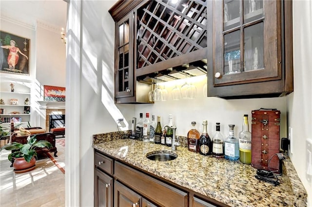 bar with a sink, ornamental molding, indoor wet bar, and a fireplace
