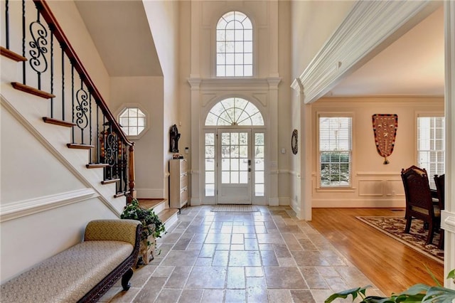 entrance foyer featuring stone tile floors, baseboards, a wealth of natural light, and a towering ceiling