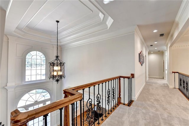 hall with visible vents, a raised ceiling, carpet, a notable chandelier, and an upstairs landing