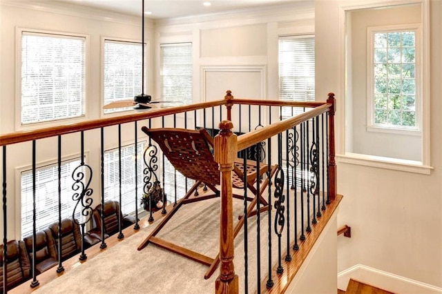 stairway featuring baseboards, plenty of natural light, ornamental molding, and ceiling fan