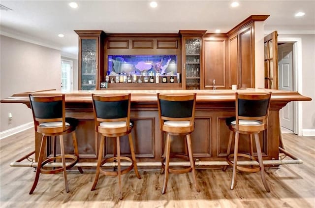 bar with baseboards, light wood finished floors, recessed lighting, and wet bar