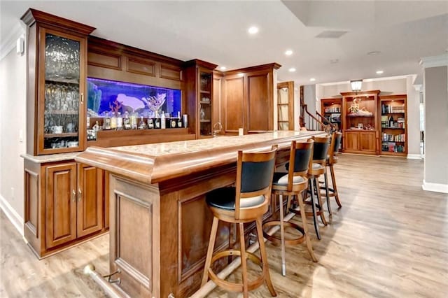 bar with crown molding, recessed lighting, baseboards, light wood-type flooring, and a bar