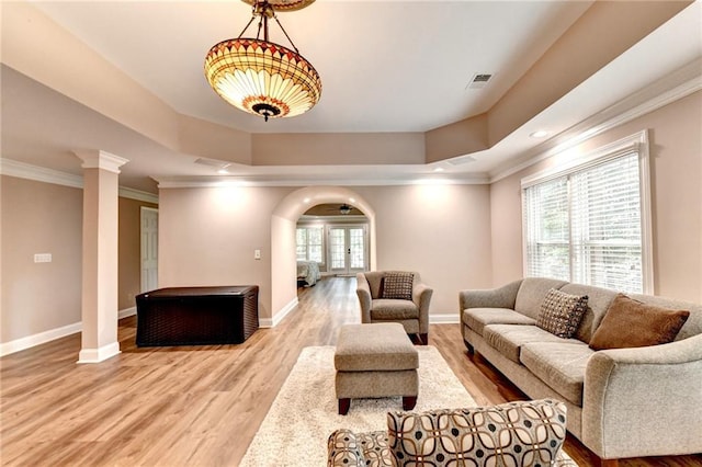 living area with baseboards, arched walkways, crown molding, and wood finished floors