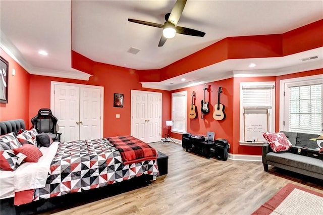 bedroom featuring crown molding, a ceiling fan, baseboards, wood finished floors, and visible vents
