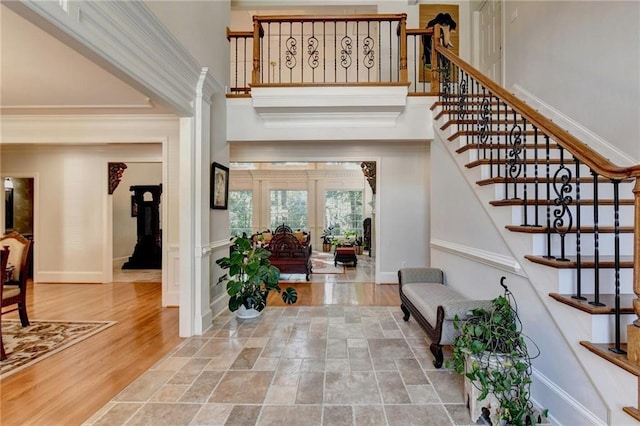 foyer featuring crown molding, baseboards, a high ceiling, stairway, and french doors