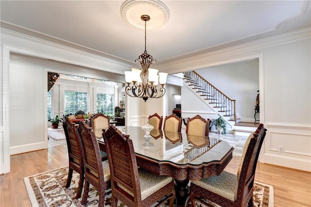 dining area with crown molding, light wood-type flooring, stairway, baseboards, and a chandelier