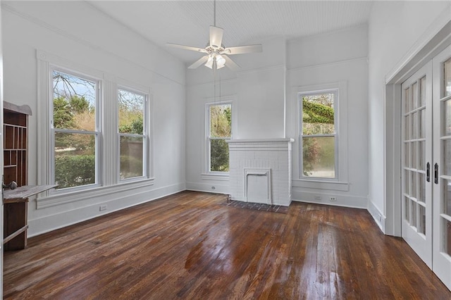 spare room featuring french doors, a brick fireplace, ceiling fan, and dark wood-type flooring