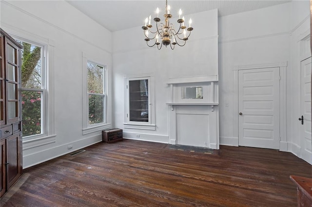 unfurnished dining area with dark wood-type flooring and an inviting chandelier