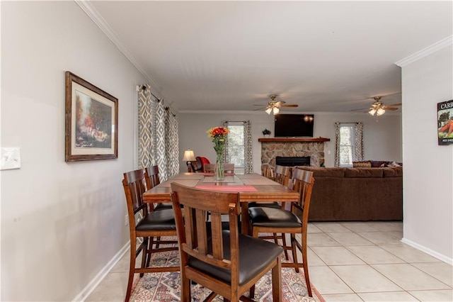 dining space with ceiling fan, crown molding, a stone fireplace, and light tile patterned flooring