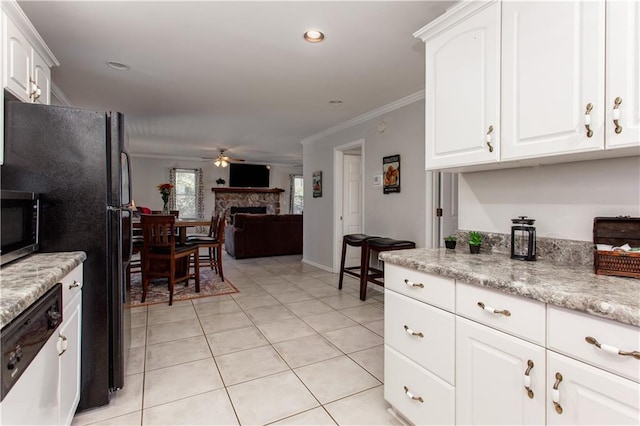 kitchen featuring stainless steel appliances, ceiling fan, a fireplace, and white cabinetry