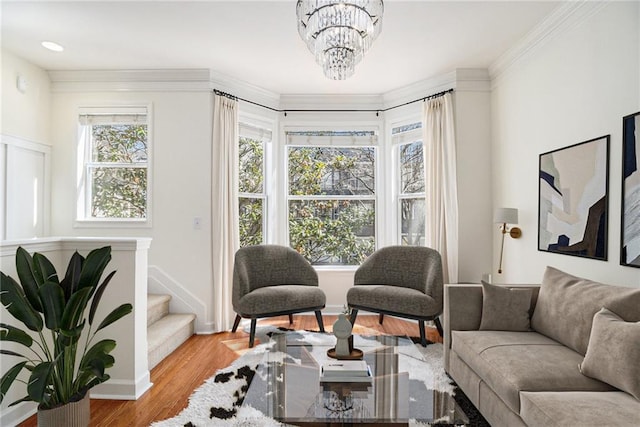 living area with light wood-type flooring, a healthy amount of sunlight, a chandelier, and crown molding