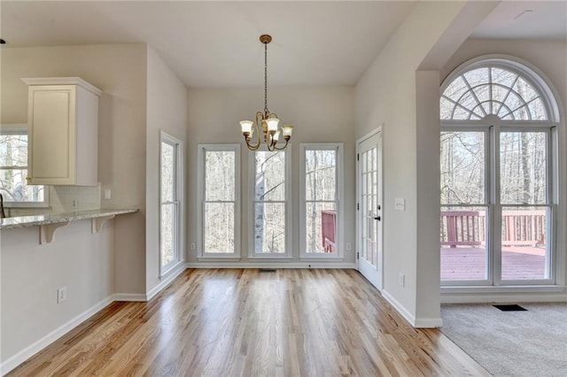 1924 Wilkenson Xing, Marietta, GA 30066 - unfurnished dining area with light wood-style flooring, a chandelier, and baseboards