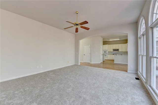 1924 Wilkenson Xing, Marietta, GA 30066 - unfurnished living room with light colored carpet, arched walkways, a ceiling fan, and baseboards
