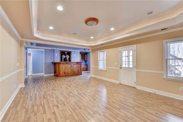 1924 Wilkenson Xing, Marietta, GA 30066 - unfurnished living room featuring a tray ceiling, ornamental molding, light wood-style floors, bar area, and baseboards