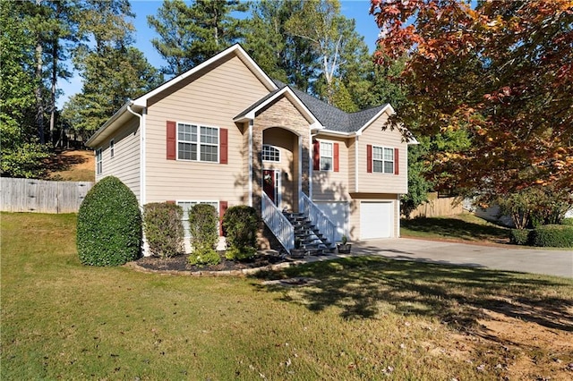 bi-level home featuring fence, concrete driveway, a front yard, stone siding, and an attached garage