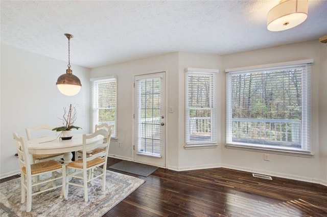 dining room with plenty of natural light, dark hardwood / wood-style floors, and a textured ceiling