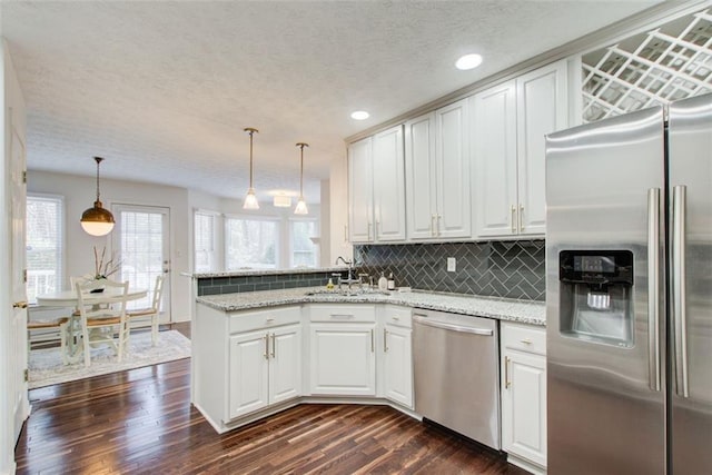 kitchen with backsplash, white cabinetry, decorative light fixtures, and appliances with stainless steel finishes