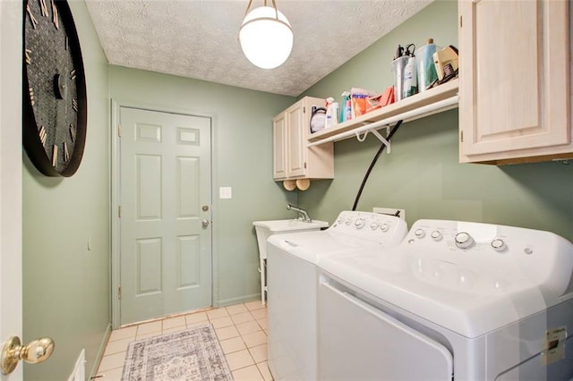 clothes washing area with cabinets, light tile patterned floors, a textured ceiling, and separate washer and dryer