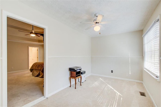 spare room with a textured ceiling, ceiling fan, light carpet, and a wealth of natural light