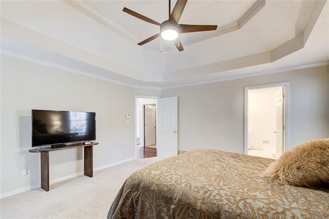 bedroom featuring a raised ceiling, ensuite bath, ceiling fan, and ornamental molding