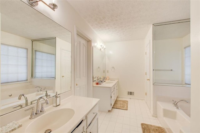 bathroom featuring vanity, a textured ceiling, a bathing tub, and tile patterned flooring