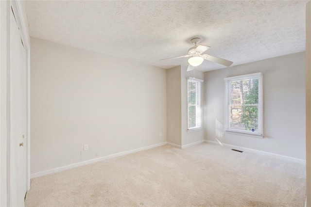 carpeted spare room featuring a textured ceiling and ceiling fan