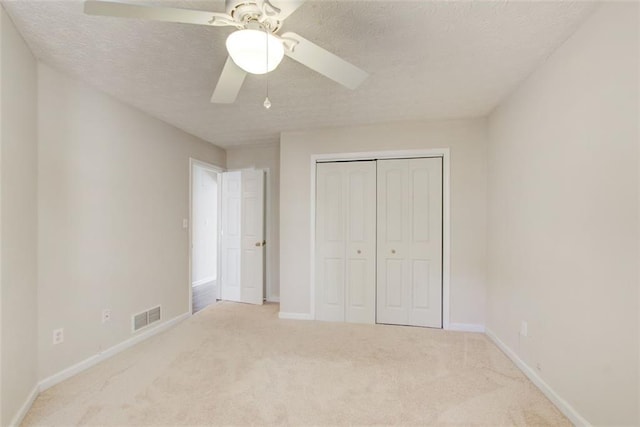 unfurnished bedroom featuring carpet, a textured ceiling, a closet, and ceiling fan