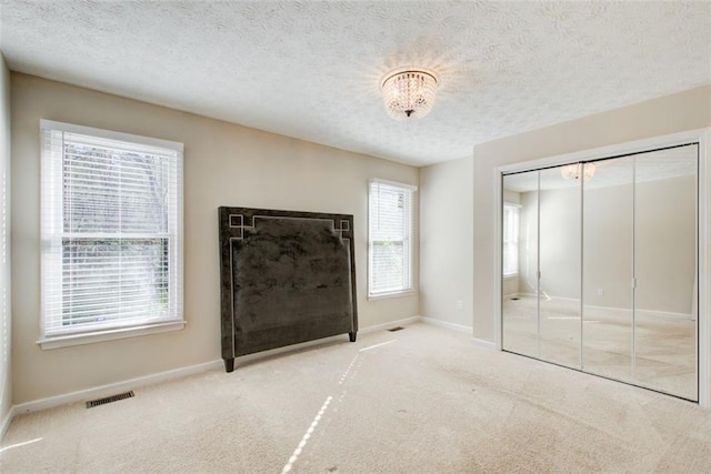 interior space with light colored carpet, a healthy amount of sunlight, and a textured ceiling