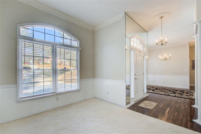 foyer entrance featuring a healthy amount of sunlight, ornamental molding, and an inviting chandelier