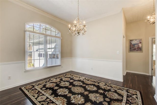 empty room featuring a chandelier, dark hardwood / wood-style flooring, and ornamental molding