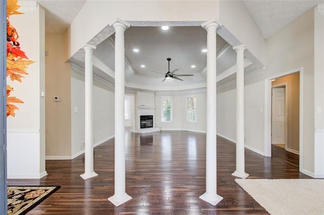 unfurnished living room with ornate columns, ceiling fan, and dark wood-type flooring