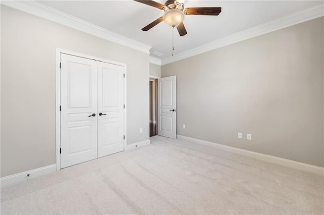 unfurnished bedroom featuring light colored carpet, a closet, ornamental molding, ceiling fan, and baseboards