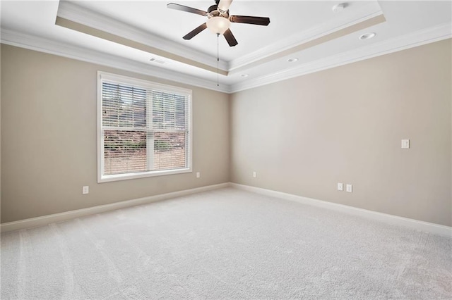 unfurnished room featuring a raised ceiling, a ceiling fan, ornamental molding, and light carpet