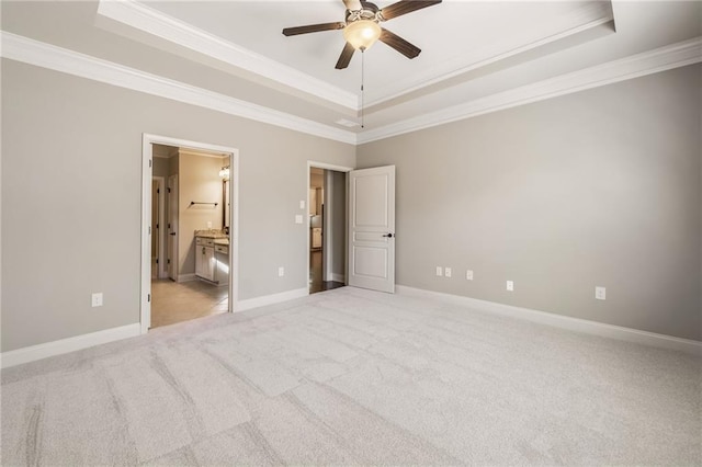 unfurnished bedroom featuring light colored carpet, crown molding, a tray ceiling, and baseboards