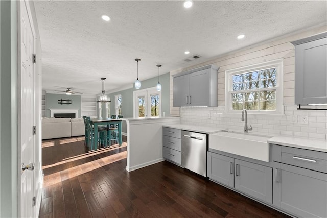 kitchen featuring gray cabinets, sink, stainless steel dishwasher, and dark wood-type flooring