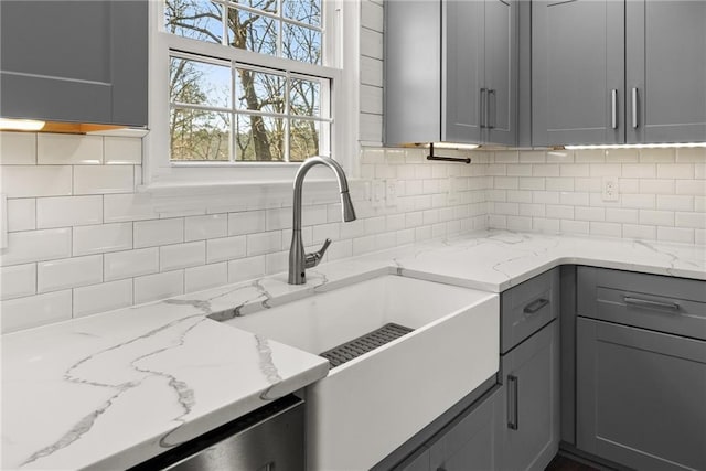 kitchen featuring gray cabinetry, sink, light stone counters, and tasteful backsplash