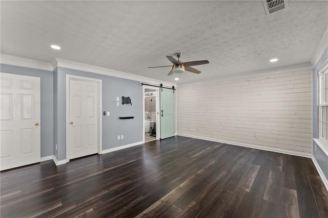 interior space with a textured ceiling, ornamental molding, dark hardwood / wood-style flooring, ceiling fan, and a barn door