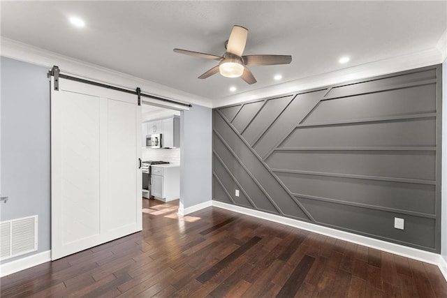 interior space with crown molding, dark wood-type flooring, a barn door, and ceiling fan